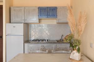 a kitchen with blue cabinets and a white refrigerator at Baia de Bahas Residence in Golfo Aranci