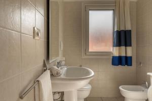 a bathroom with a sink and a toilet and a window at Baia de Bahas Residence in Golfo Aranci