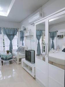 a white room with a tv and a bed at Prathana Garden Beach Resort in Hua Hin