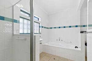 a white bathroom with a tub and a sink at Black Dolphin Waterfront Apartment in San Remo