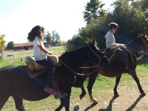 two people riding on the backs of horses at Hotel Haras Casacampo in Quintero