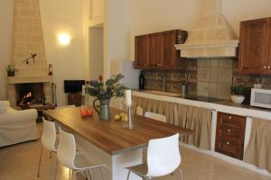 cocina con mesa de madera y sillas blancas en Masseria Zambardo, en San Vito dei Normanni