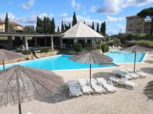 una piscina con sillas y sombrillas y una piscina en Apartment Il Felciaione-8 by Interhome, en Riparbella