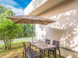 a wooden table with chairs and an umbrella at Apartment Barbara-2 by Interhome in Santa Luce