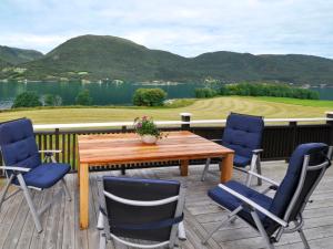 een houten tafel en stoelen op een terras met uitzicht op een meer bij Chalet Bøgeilen - FJM303 by Interhome in Heggem