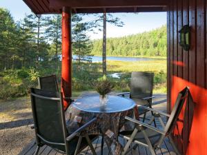 een tafel en stoelen op een veranda met uitzicht op een meer bij Chalet Holmestua - SOO398 by Interhome in Arendal