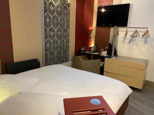 a hotel room with a large bed and a desk at Hôtel Le Dormeur du Val in Charleville-Mézières