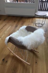 une chaise en cuir blanc assise au-dessus d'un parquet dans l'établissement Apartment Turmalin 2- Stock by Interhome, à Lenk im Simmental