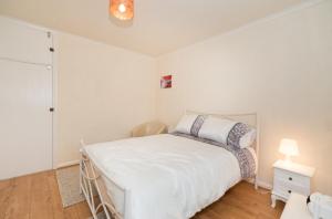 a white bedroom with a bed and a lamp at TDM Bachelot Lettings Ltd in London
