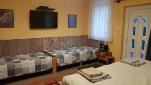 a hotel room with two beds and a flat screen tv at Levendul&aacute;s Vend&eacute;gh&aacute;z in Zalaegerszeg