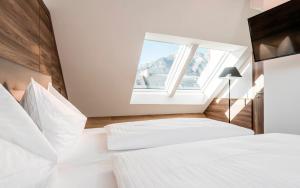 een slaapkamer met 2 witte bedden en een raam bij Hotel Zach in Innsbruck