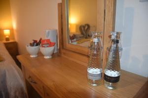 duas garrafas numa cómoda de madeira em frente a um espelho em The Old Silent Inn em Haworth
