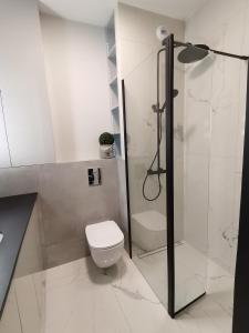 a white bathroom with a toilet and a shower at Luxusowy Apartament Klimczaka in Warsaw
