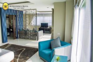 a living room with a blue chair and a desk at SR Residence Hotel in Phetchabun