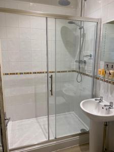 a shower with a glass door next to a sink at Inn in the Park in Bournemouth