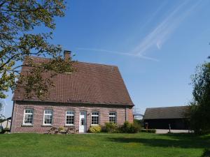 ein Backsteinhaus mit einem Dach auf einem Grasfeld in der Unterkunft Landhaus Holthausen in Werne an der Lippe