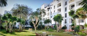 een groot wit gebouw met palmbomen ervoor bij Apartamento en Jardines del Puerto in Marbella