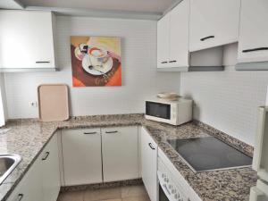 een keuken met witte kasten en een magnetron bij Apartamento en Jardines del Puerto in Marbella