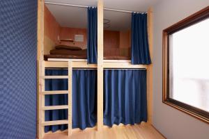 a bunk bed with blue curtains and a ladder at Guesthouse OYADO SAPPORO in Sapporo