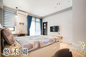 a bedroom with a bed and a tv on a wall at Host Garden悠禾園 in Hualien City