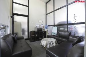 a living room with black leather furniture and windows at Hotel Hue Loft in Incheon