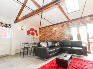 a living room with a black leather couch and a brick wall at 4 Holt Court in Salisbury