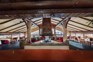 a large room with a fireplace and tables and chairs at Hotel Alpen Roc in La Clusaz