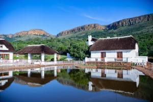 a house with a thatched roof and a reflection in the water at Steynshoop self-catering Valley Lodge in Hekpoort