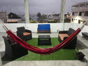 a hammock on a balcony with chairs and a table at Costa Del Sol in Puerto Ayora