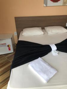 two beds in a room with a black blanket on them at Don Charleaux Hotel in Aparecida