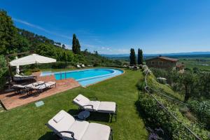 una piscina con sillas y una sombrilla en un patio en Luxury 6-bed Tuscan Villa near Lucca, en Castelvecchio