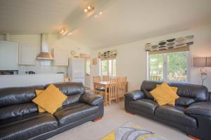 a living room with two leather couches and a kitchen at Puddleduck Lodge with Hot Tub on Felmoor Park in Morpeth