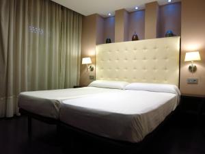 un grande letto bianco in una stanza con due lampade di Apartamentos Boutique Catedral a Valladolid