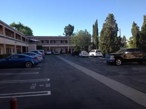 Un estacionamiento con autos estacionados frente a un edificio. en New Century Inn, en San Gabriel