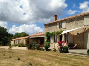 una vecchia casa in pietra con un cortile davanti di Villa élégante à Saint-Cyr-en-Talmondais avec piscine privée a Saint-Cyr-en-Talmondais