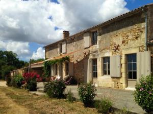 una vecchia casa in pietra con dei fiori davanti di Villa élégante à Saint-Cyr-en-Talmondais avec piscine privée a Saint-Cyr-en-Talmondais