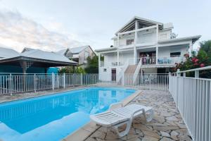 a house with a swimming pool and a white fence at Appartement d'une chambre avec piscine partagee jardin et wifi a Sainte Anne a 3 km de la plage in Sainte-Anne