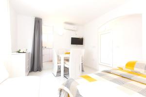 a white bedroom with two beds and a table at One bedroom house at Skrpcici 500 m away from the beach with enclosed garden and wifi in Skrbčići