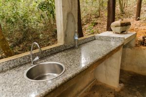 a sink with a bottle of water on a counter at Chalés do Beto em Macacos in Macacos +115 photos