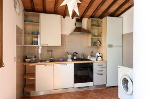 uma cozinha com armários brancos e um frigorífico branco em 3 bedrooms villa with private pool jacuzzi and enclosed garden at Le Scotte em Siena