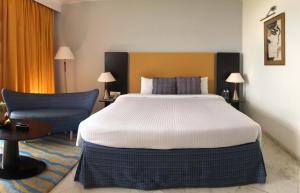 a bedroom with a large bed and a blue chair at The Park Visakhapatnam in Visakhapatnam