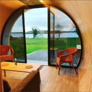 a room with a table and chairs and large windows at Further Space at Carrickreagh Bay Luxury Glamping Pods, Lough Erne in Enniskillen