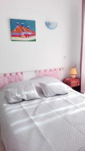 1 Schlafzimmer mit einem weißen Bett mit einem rosa Kopfteil in der Unterkunft Maison de 2 chambres avec jardin clos et wifi a Sourdeval in Sourdeval