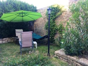 un parasol vert assis à côté d'une chaise et d'une lampe dans l'établissement Maison de 3 chambres avec jardin clos et wifi a Nuits Saint Georges, à Nuits-Saint-Georges