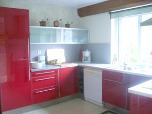 a kitchen with red cabinets and a sink and a window at Maison confortable à Lunas avec vue montagne + jardin in Lunas