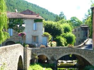 a stone bridge over a river in a village at Maison confortable à Lunas avec vue montagne + jardin in Lunas +4 photos