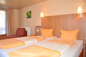 una habitación de hotel con 2 camas y una silla en Gazauner Hof, en Sankt Gallenkirch