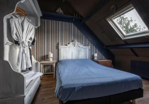 a bedroom with a blue bed and a window at Smederij Texel in De Cocksdorp