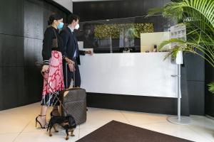 due persone con un cane in piedi davanti a un bancone di Marconi Hotel a Rende