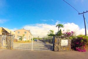 a white gate in front of a house with flowers at 2 bedrooms villa at Grand Gaube 800 m away from the beach with private pool enclosed garden and wifi in Grande Gaube